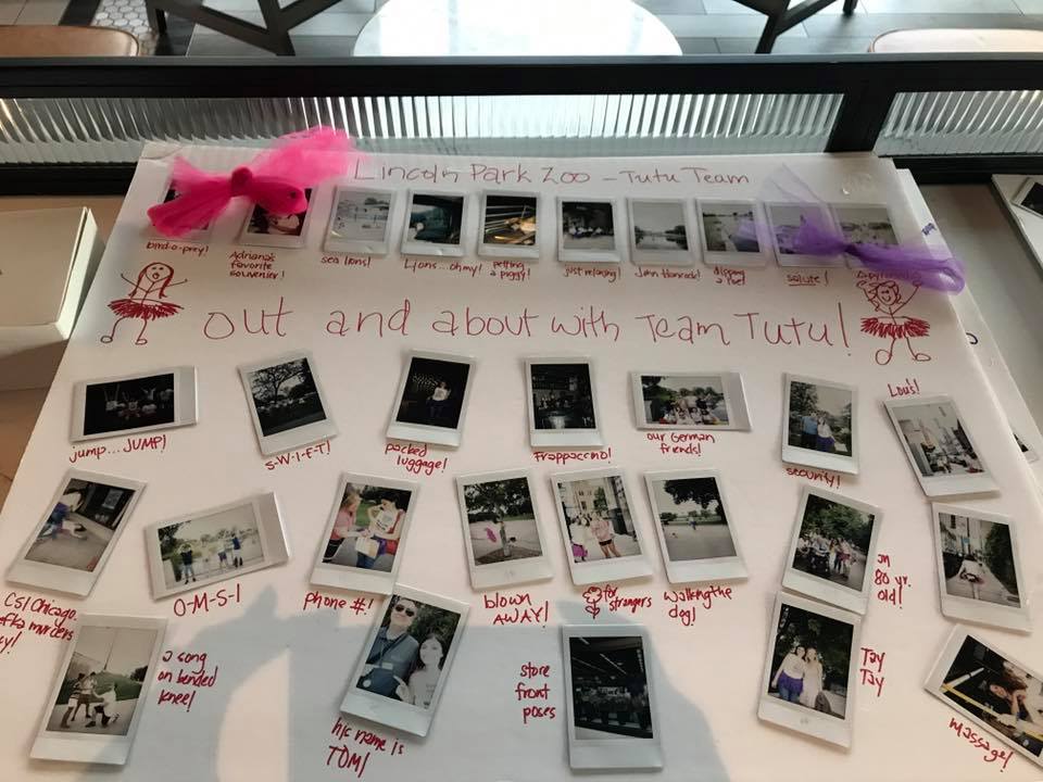 A display board from a Polaroid scavenger hunt themed 'Out and About with Team Tutu.' The board features instant photos taken at Lincoln Park Zoo, adorned with hand-drawn stick figures in tutus and decorated with small pink and purple tutu accents. Each photo is captioned with playful notes about team challenges and activities, showcasing the fun and lighthearted atmosphere of this creative team building event.