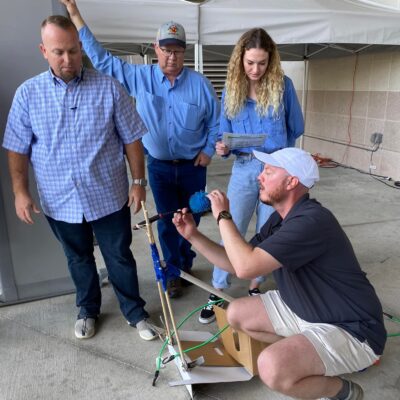 A group of four participants outdoors working together to assemble a small catapult during the Catapult to Success team building activity, emphasizing teamwork, innovation, and hands-on problem-solving.