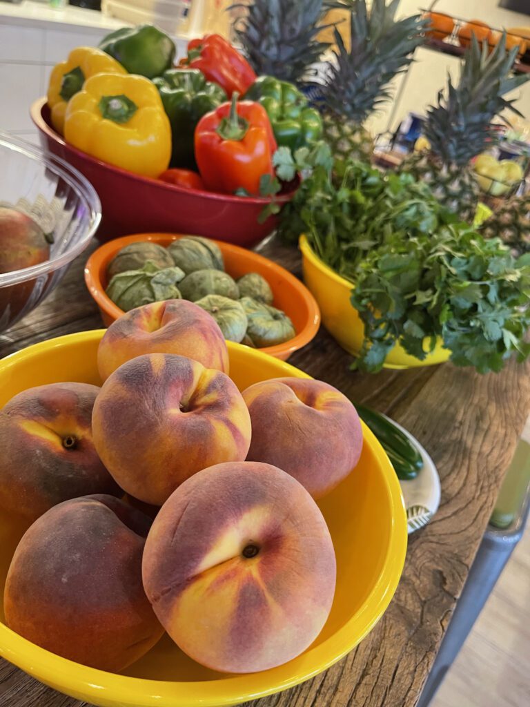 Fresh peaches, bell peppers, pineapples, and cilantro displayed at a Salsa Showdown, ready to be transformed into flavorful salsa creations.