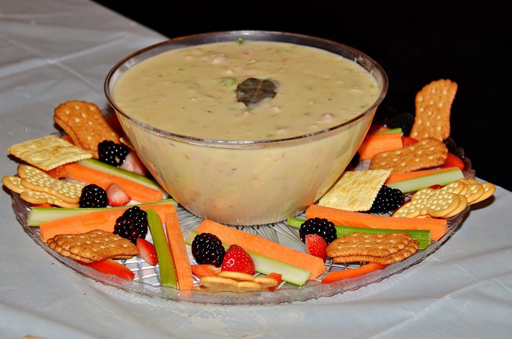 Bowl of chowder surrounded by crackers, fresh vegetables, and berries at the Wicked Good Chowda Cook-Off team building event.