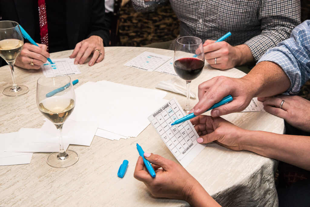 Close-up of players marking their bingo cards with colorful markers during a Wild Card Team Building Bingo event.