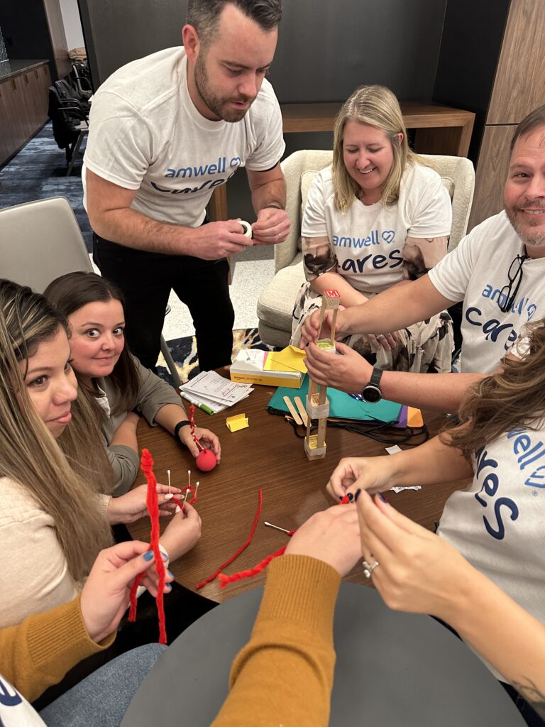 Team of participants working together on a crafting activity during a CSR event. They are creating handmade items as part of a team building project aimed at supporting a cancer patients.