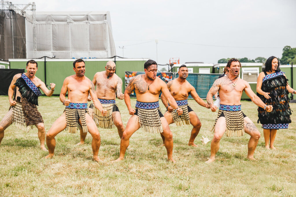 Team building participants performing a traditional Haka dance, led by Maori facilitators in traditional attire.