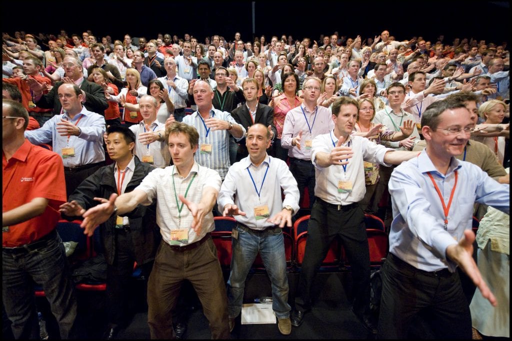 Large group of participants standing together in unison, performing synchronized Haka dance moves during a team building event.