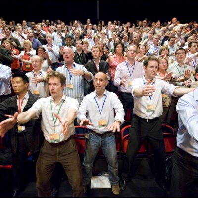 Large group of participants standing together in unison, performing synchronized Haka dance moves during a team building event.