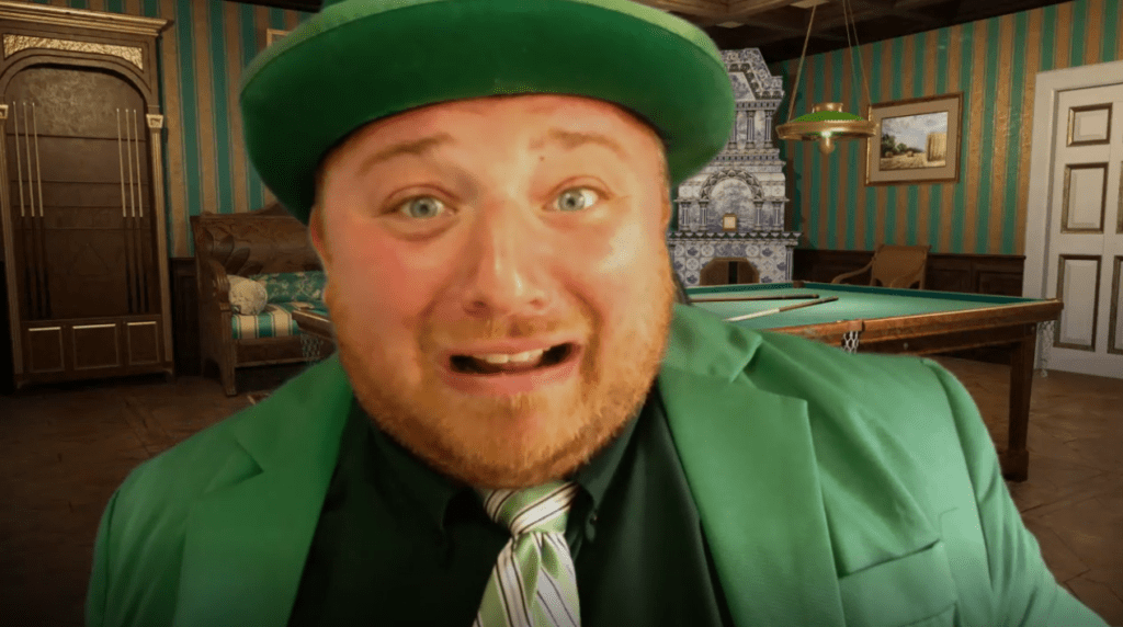 A man wearing a bright green suit, green tie, and matching green hat is seen in the foreground with an exaggerated, nervous expression on his face. The man’s expression and vivid outfit create a humorous and lively atmosphere. He's role-playing in a murder mystery team building event.