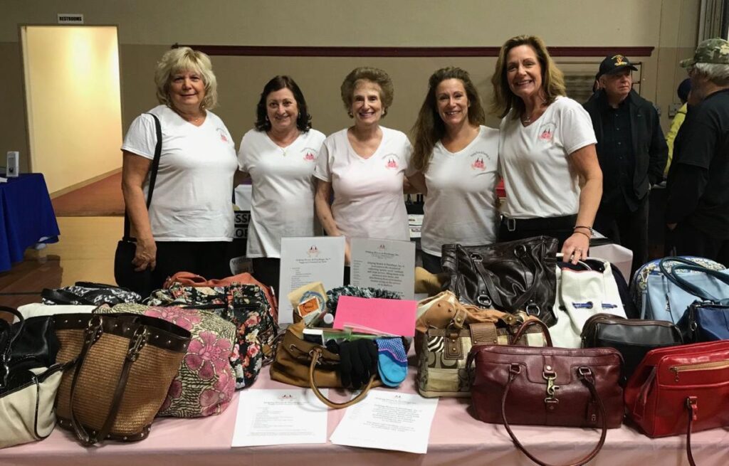 Participants proudly display filled handbags during the Hopefull Handbags Global team building event, supporting survivors of domestic abuse with essential items and hope.