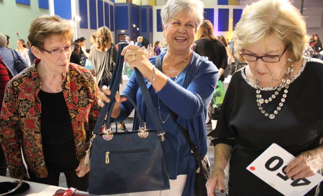 Participants selecting handbags for donation during a Hopefull Handbags Global team building event, supporting survivors of domestic abuse with essential items and hope.