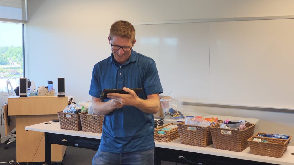 Participant smiling during a Hopefull Handbags Global team building event, where baskets of essential items are ready to be packed into handbags for donation to women survivors of domestic abuse.