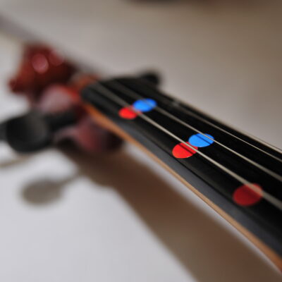 Close-up of a violin’s fingerboard with colorful markers to help participants learn notes quickly during the Crescendo team building event.