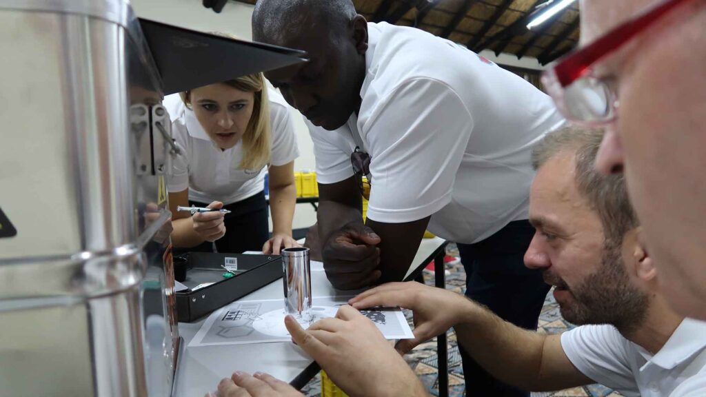 Team members intensely focus on solving puzzles from a metal case during the 'Atmosphere' team building event, working together to unlock critical clues.