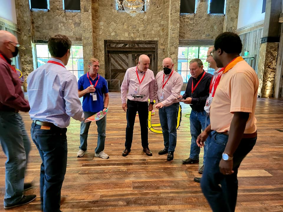 A group collaborates and strategizes during the Game of Drones team building event, working together to maneuver their drone through obstacles.