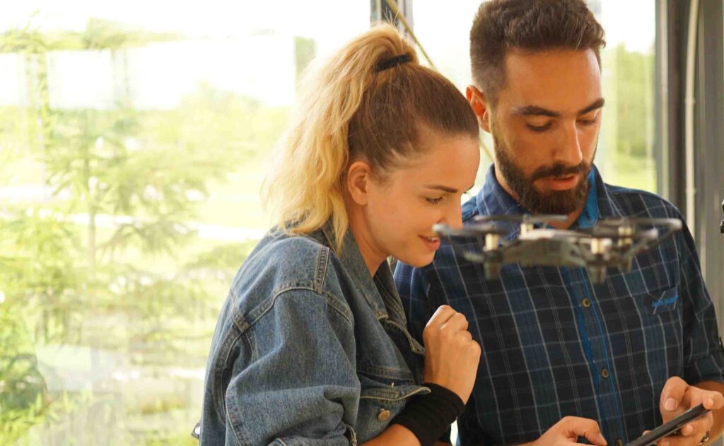 Two participants control a drone during the Game of Drones team building event, showcasing collaboration and hands-on technology.