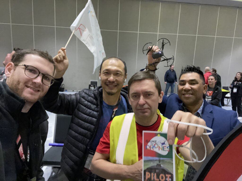 A group of drone pilots proudly display their pilot badge and drone during the Game of Drones team building event, ready for some high-flying fun and competition.