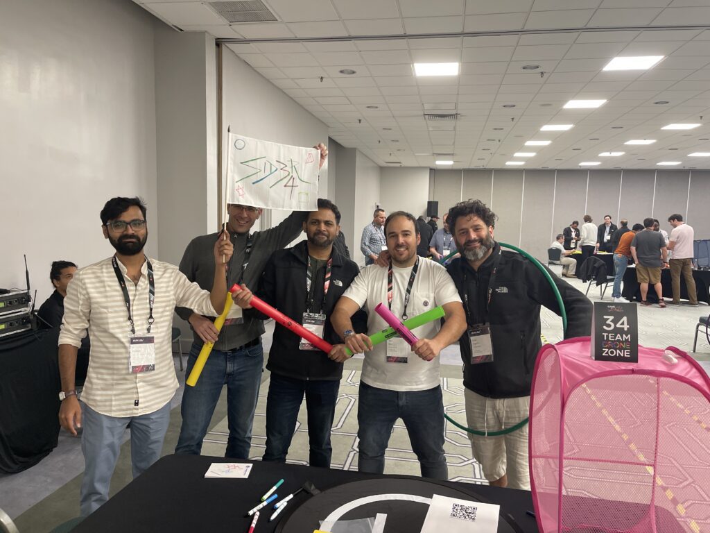 A team stands proudly with colorful drone navigation props during the Game of Drones team building event, ready to take on the challenges ahead.