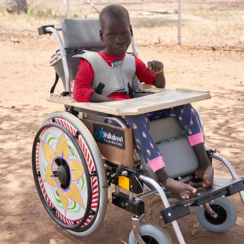 A young child seated in a newly decorated wheelchair provided by the Walkabout Foundation during the Wheels Around the World team building event.