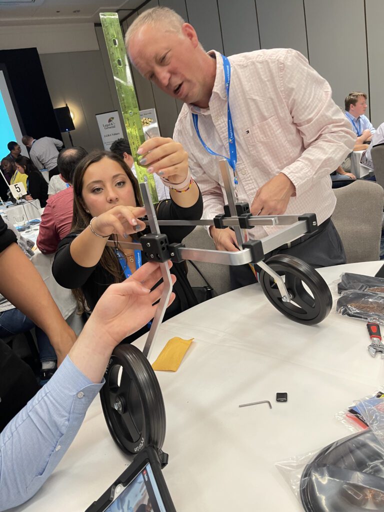 Two participants assemble a pet wheelchair by adjusting its frame and securing parts. Their concentration reflects the collaborative effort required to ensure the device is functional, highlighting teamwork and problem-solving in this meaningful activity.