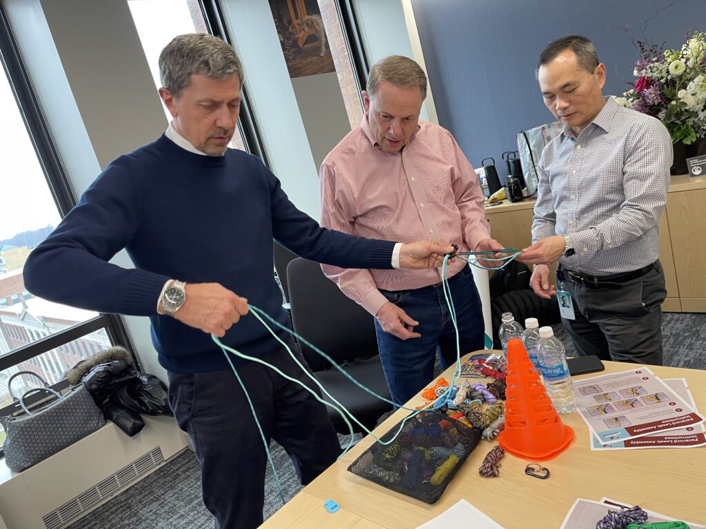 Three participants work together to tie ropes during the Mission ImPAWssible team building activity.
